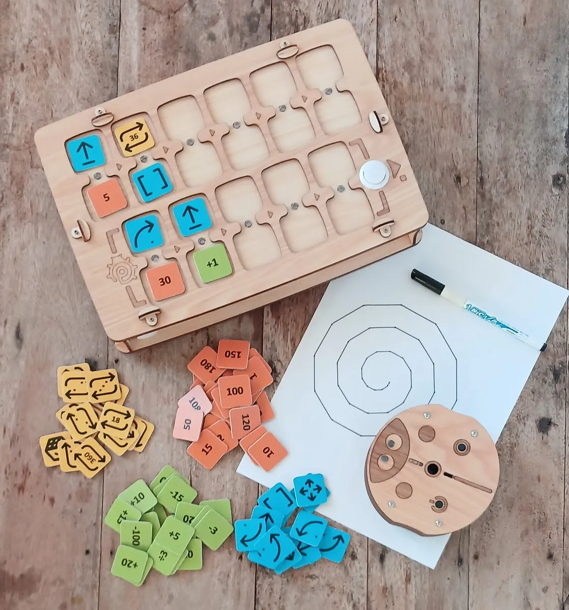 PrimaSTEM complete kit: wooden control board with colorful command tokens, ladybug robot, and drawings made by the robot